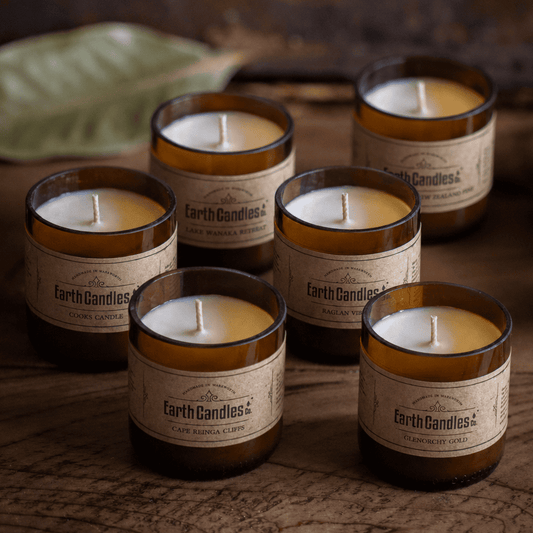 Six soy tealights in cut amber beer bottle bases, each a different Earth Candles Co. fragrance