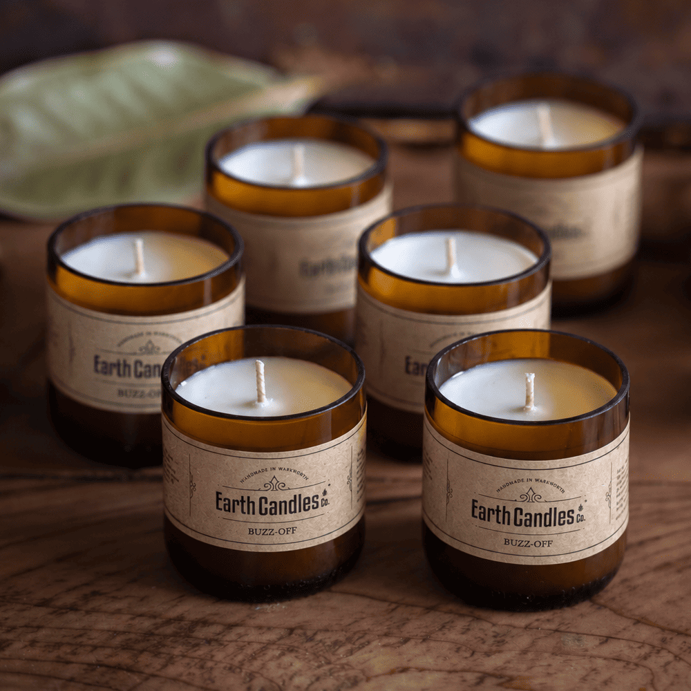 Six Buzz-Off soy tealights, unlit, grouped in their cut amber beer bottle bases