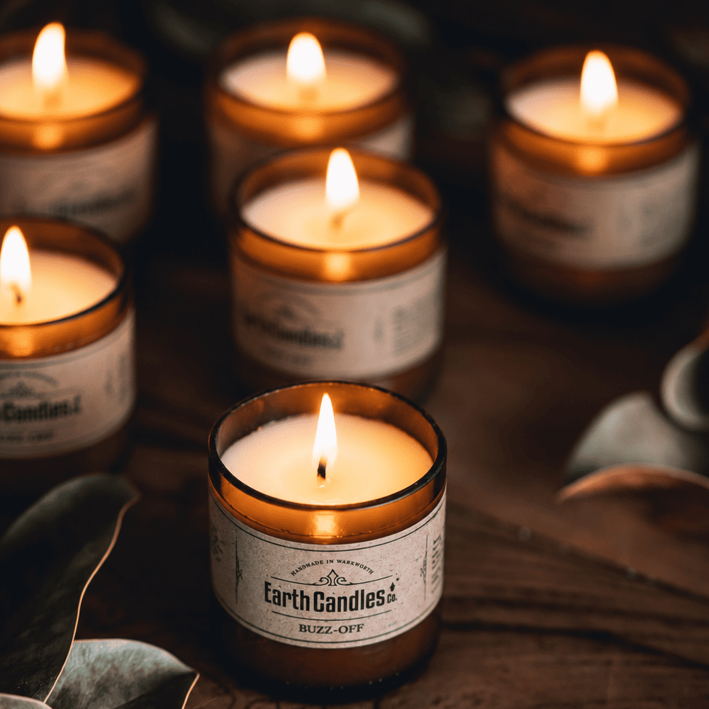 Six Buzz-Off soy tealights burning together in cut amber beer bottle bases