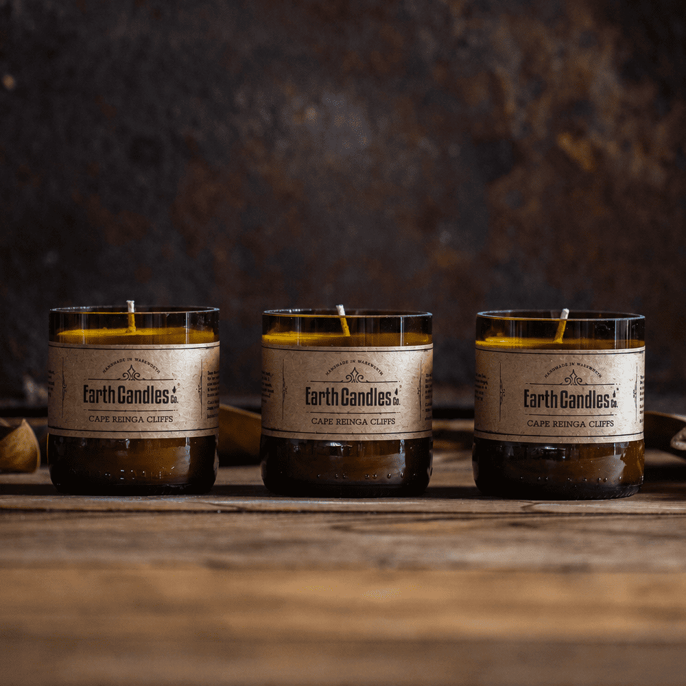 Three Cape Reinga Cliffs soy tealights by Earth Candles Co., unlit, in cut amber beer bottle bases