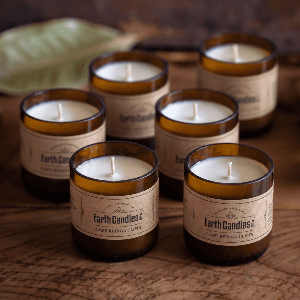 Six Cape Reinga Cliffs soy tealights, unlit, grouped in their cut amber beer bottle bases