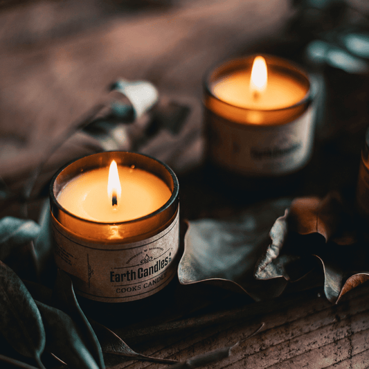 Cooks Candle soy tealights burning in cut amber beer bottle bases among dried leaves