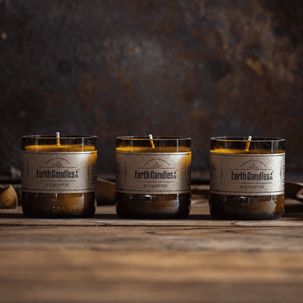 Three Eucalyptus soy tealights by Earth Candles Co., unlit, in cut amber beer bottle bases