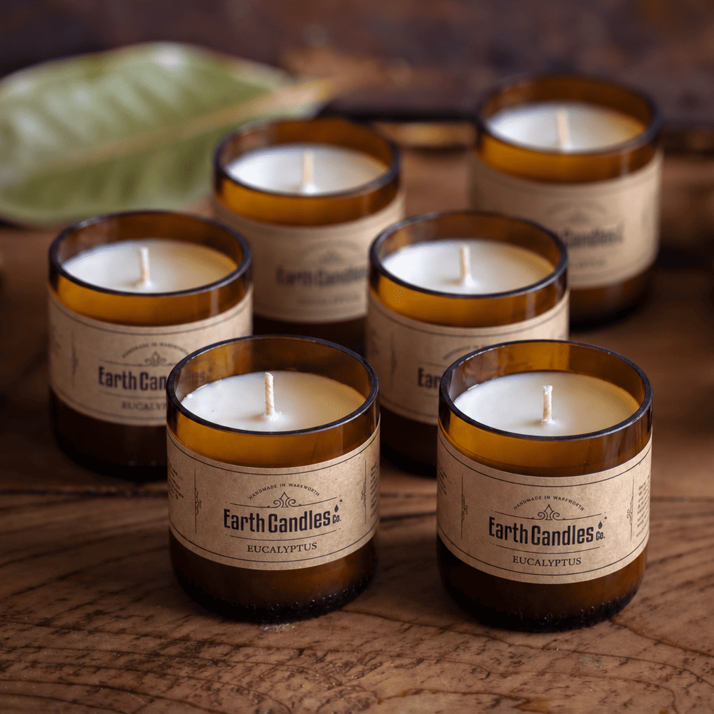 Six Eucalyptus soy tealights, unlit, grouped in their cut amber beer bottle bases