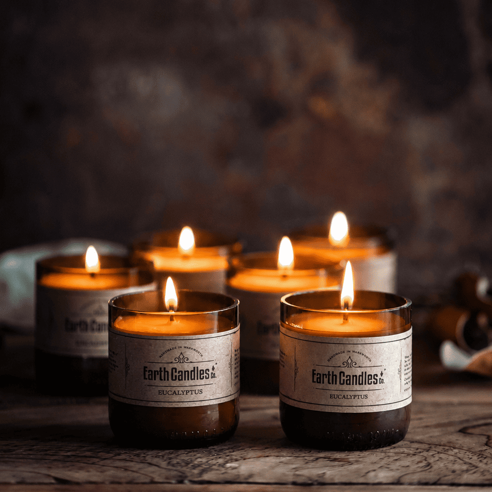 Six Eucalyptus soy tealights burning together in cut amber beer bottle bases