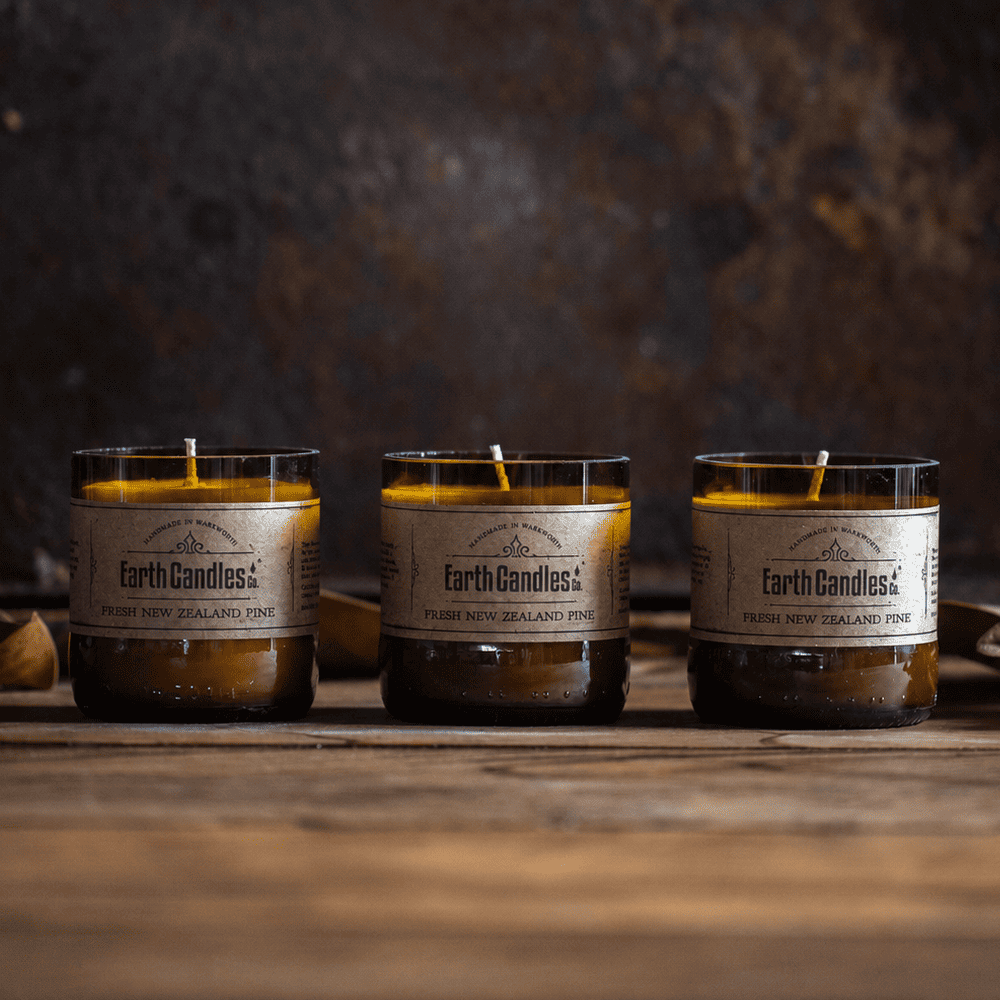 Three Fresh New Zealand Pine soy tealights by Earth Candles Co., unlit, in cut amber beer bottle bases