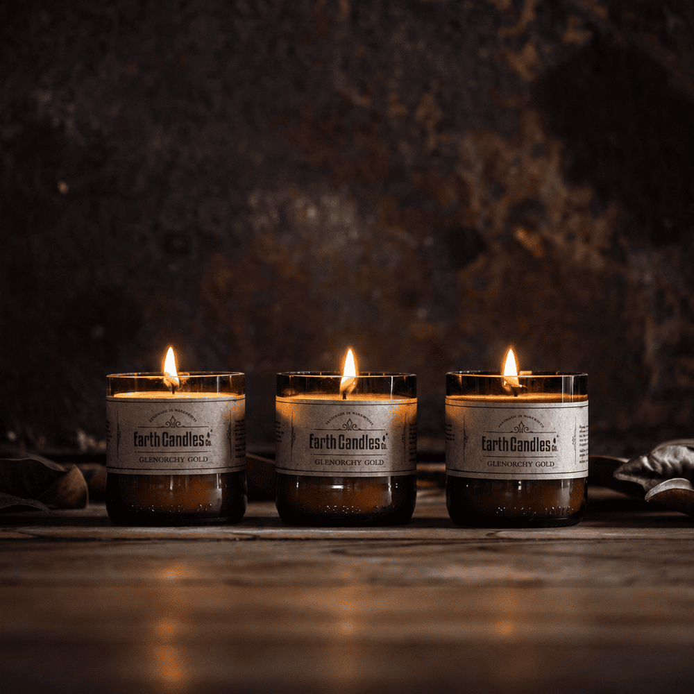 Three Glenorchy Gold soy tealights burning in a row in cut amber beer bottle bases