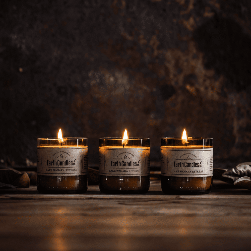 Three Lake Wanaka Retreat soy tealights burning in a row in cut amber beer bottle bases