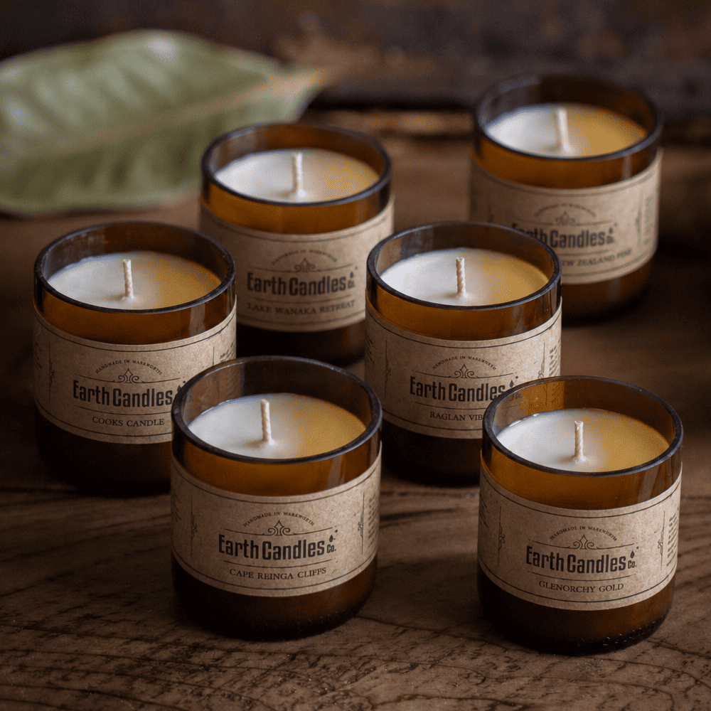 Six soy tealights in cut amber beer bottle bases, each a different Earth Candles Co. fragrance
