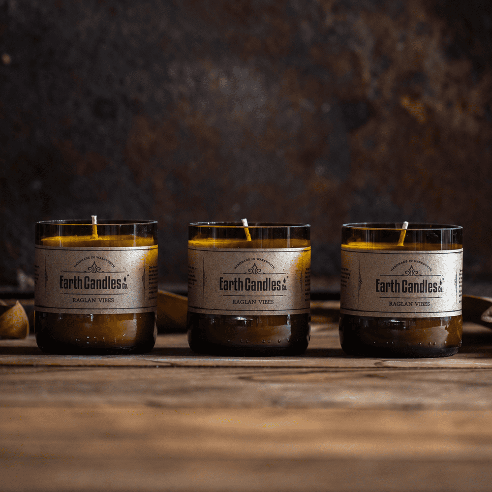 Three Raglan Vibes soy tealights by Earth Candles Co., unlit, in cut amber beer bottle bases
