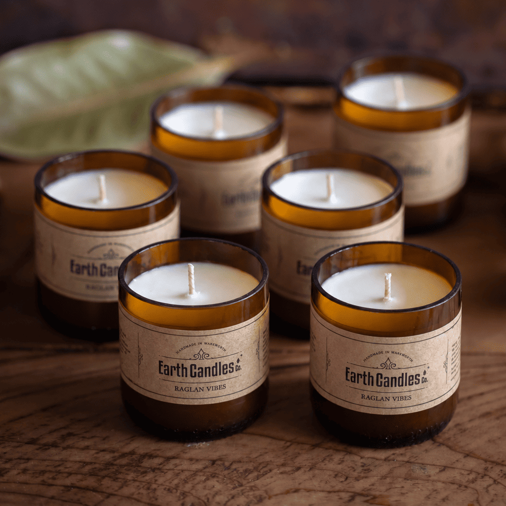 Six Raglan Vibes soy tealights, unlit, grouped in their cut amber beer bottle bases