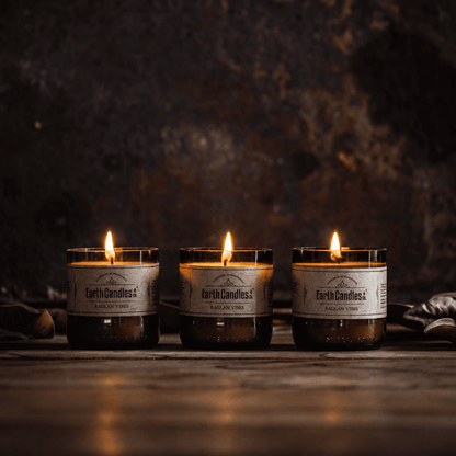 Three Raglan Vibes soy tealights burning in a row in cut amber beer bottle bases