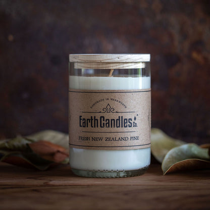 A soy candle in a repurposed wine bottle with a label that reads 'Earth Candles - Fresh New Zealand Pine'.